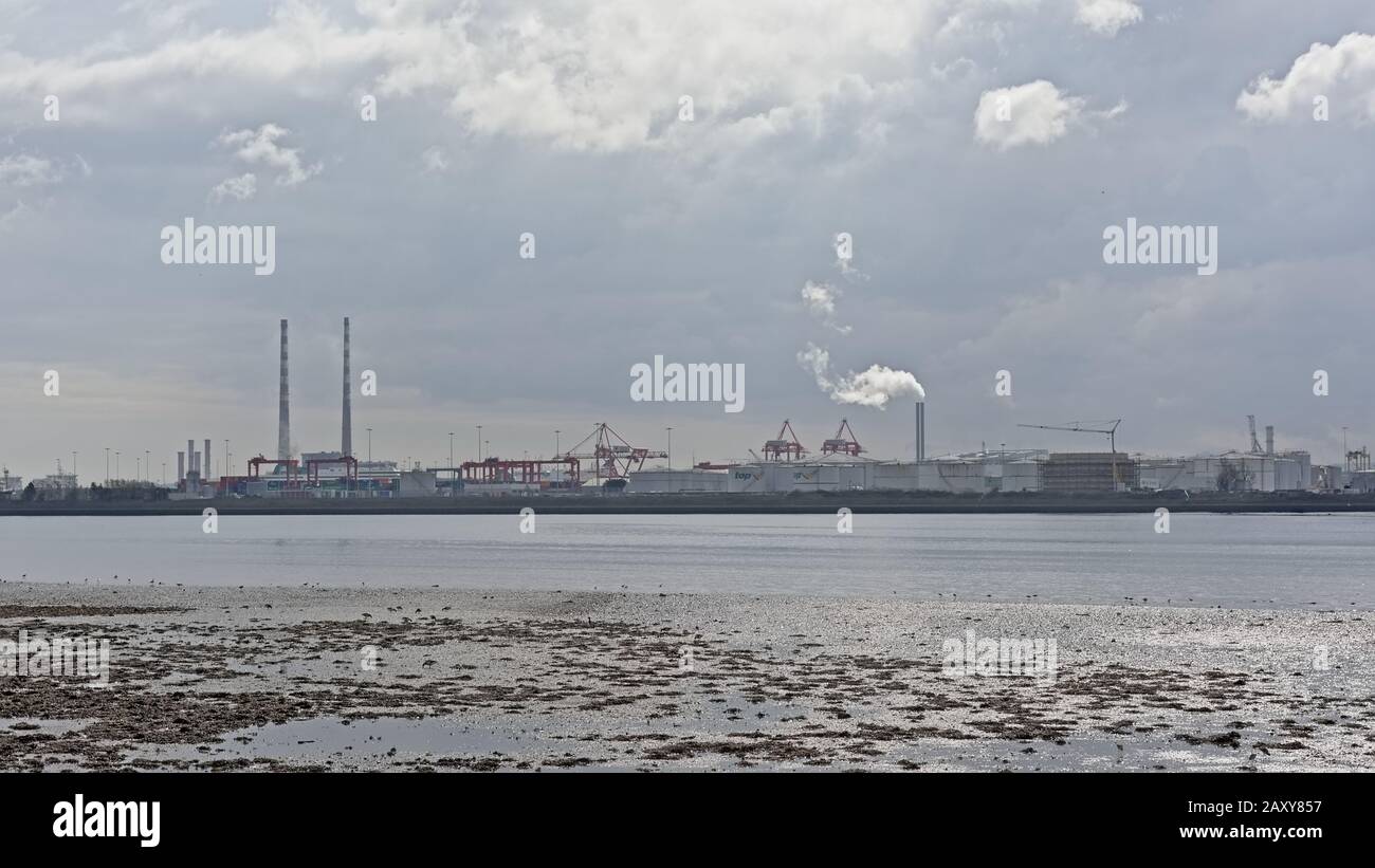 Vista Misty dall'altra parte dell'acqua sulla penisola di Poolberg, con i camini della centrale elettrica e gru industriali e gli edifici portuali Foto Stock