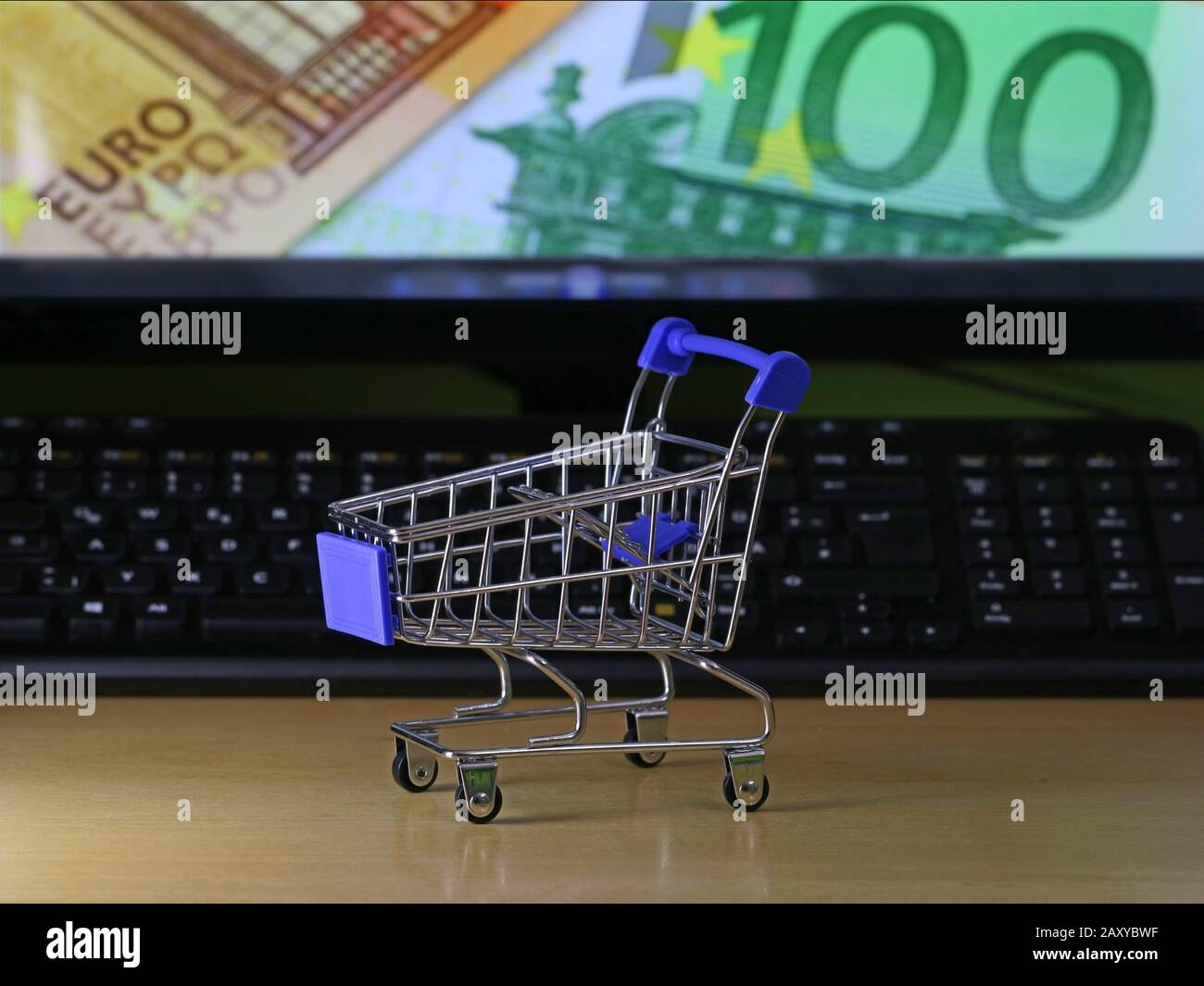 carrello su banco di legno con banconote in euro sullo schermo, concetto di shopping online Foto Stock