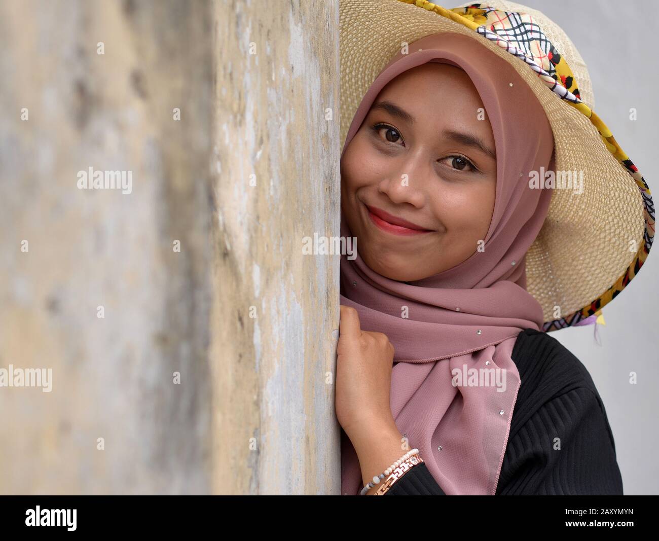 Bella giovane malese donna malese indossa un moderno cappello da sole con il suo hijab tradizionale e pone per la macchina fotografica. Foto Stock