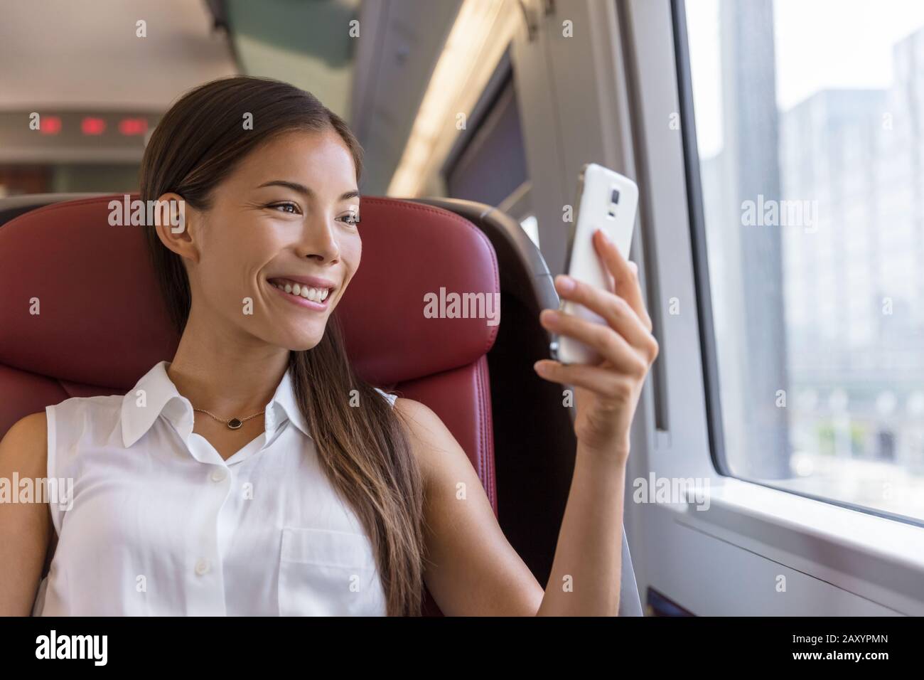 Donna asiatica che utilizza l'app per smartphone per scattare foto della vista mentre viaggi in treno. Felice giovane signora guardare video tenendo telefono cellulare durante il trasporto in vacanza di viaggio. Foto Stock