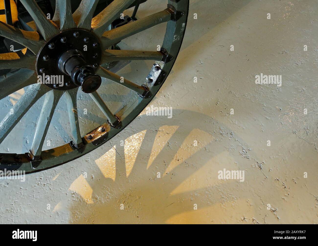 Una ruota di un vecchio cannone con ombra sul pavimento in cemento Foto Stock