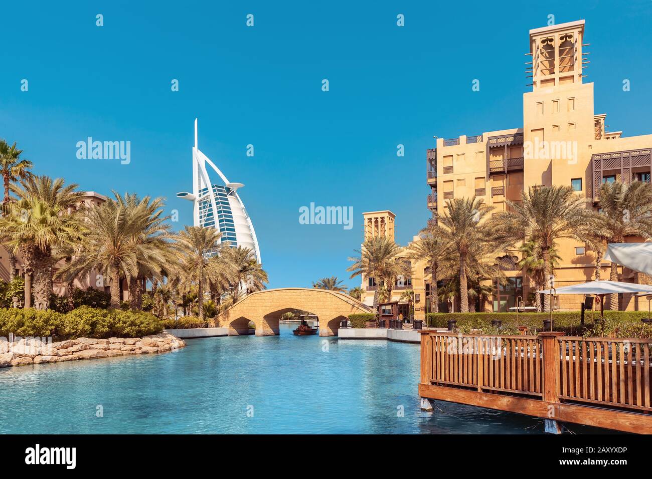 Vista dell'elegante hotel a sette stelle Burj al Arab a forma di vela e del canale artificiale con un ponte Foto Stock