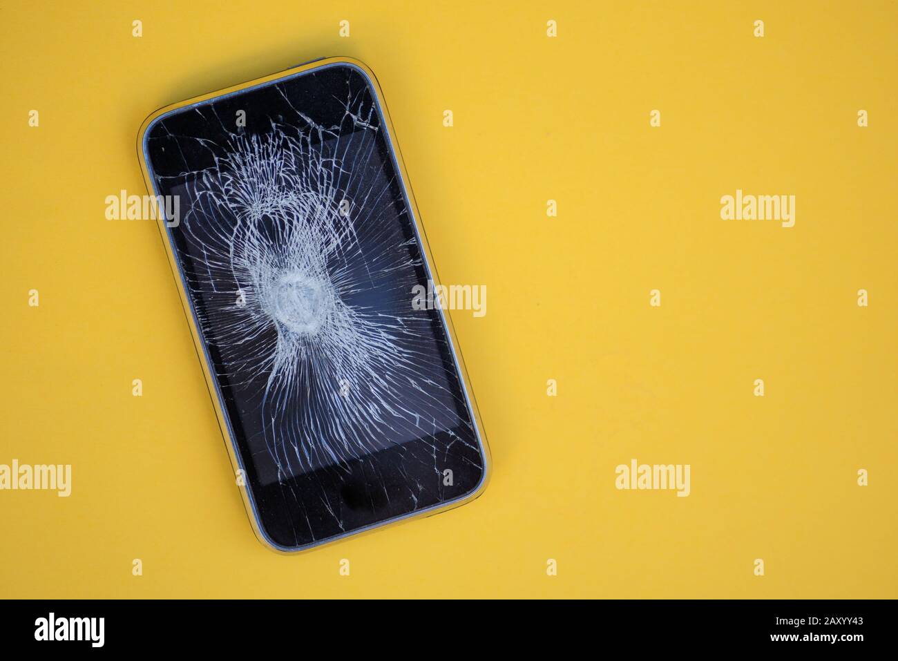 Telefono con schermo incrinato isolato su sfondo giallo Foto Stock