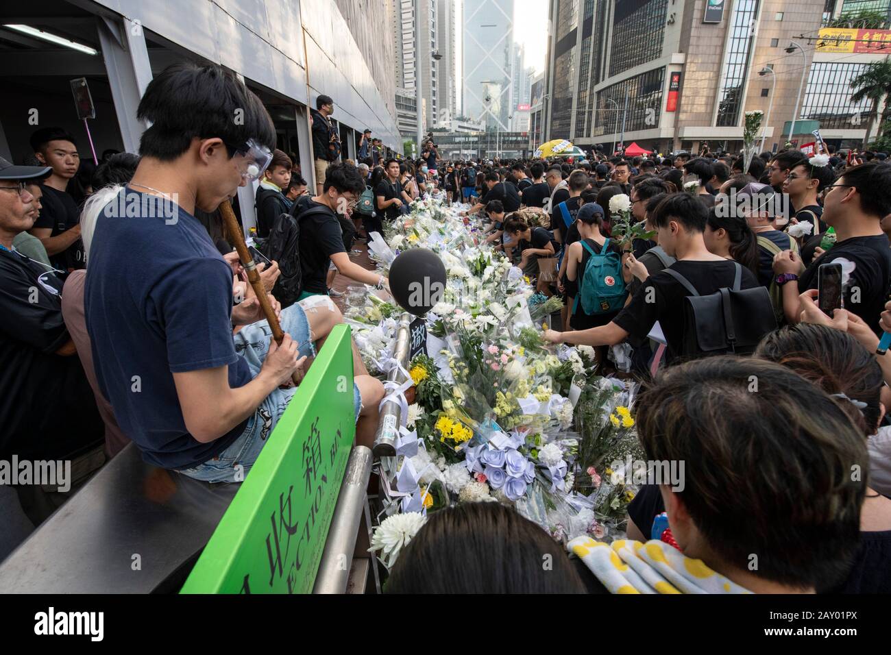 Hong Kong, Cina: 16 Giu 2019. Un protester suona la musica sul flauto mentre altri posizionano i fiori in un memoriale al centro commerciale Pacific Place ad Ammiragliato Foto Stock