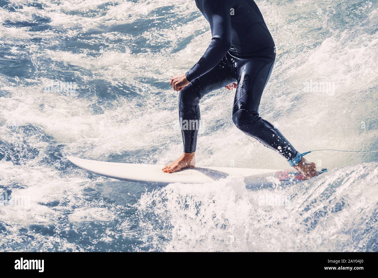 Primo piano sulle gambe di un atleta che surfing sulle onde del mare Foto Stock