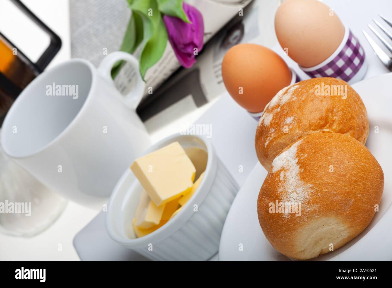 uova, panini, burro e caffè su sfondo bianco Foto Stock