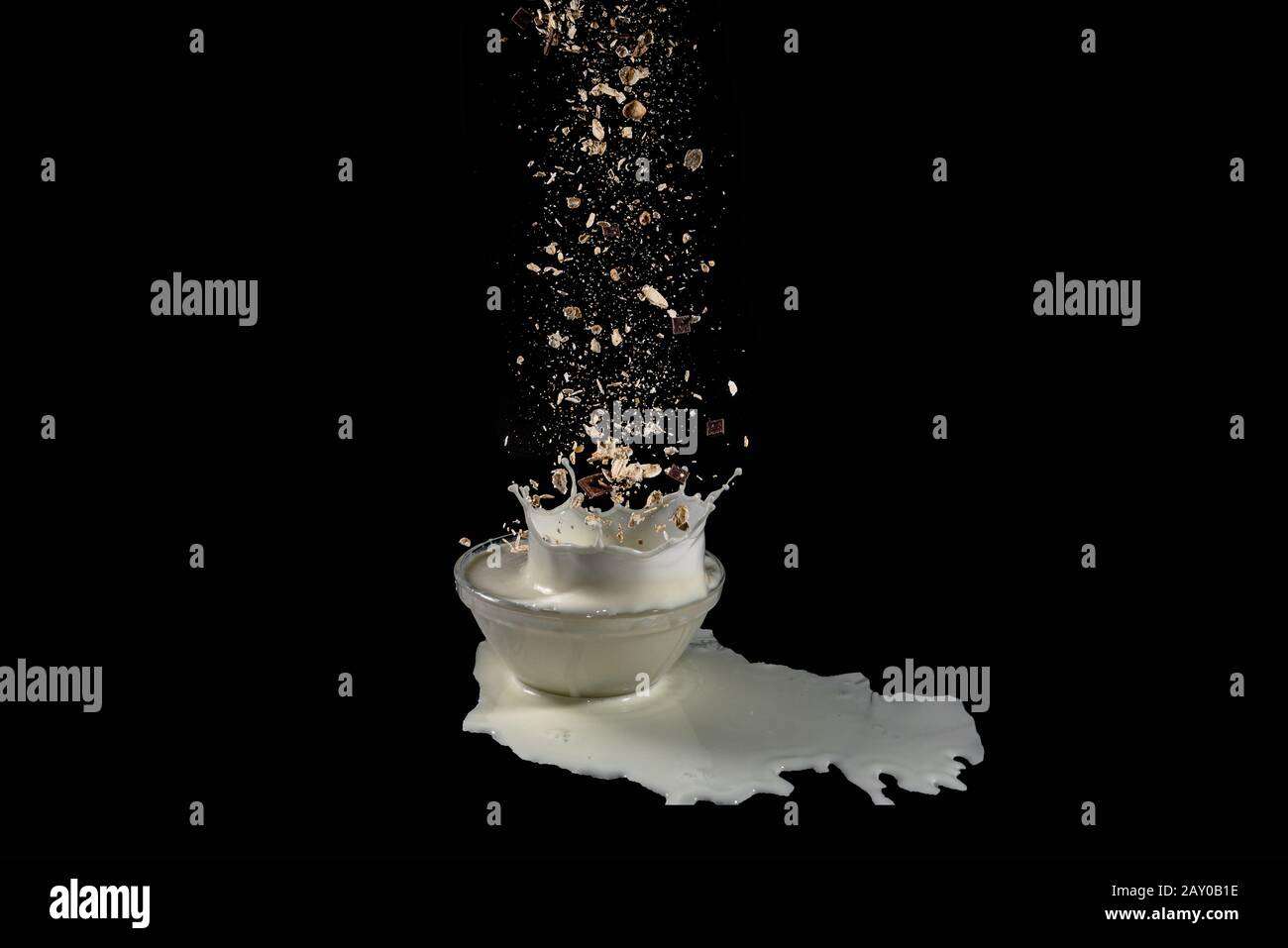 i cereali che si levitano cadono in una ciotola con il latte schizzato - immagine ad alta velocità Foto Stock