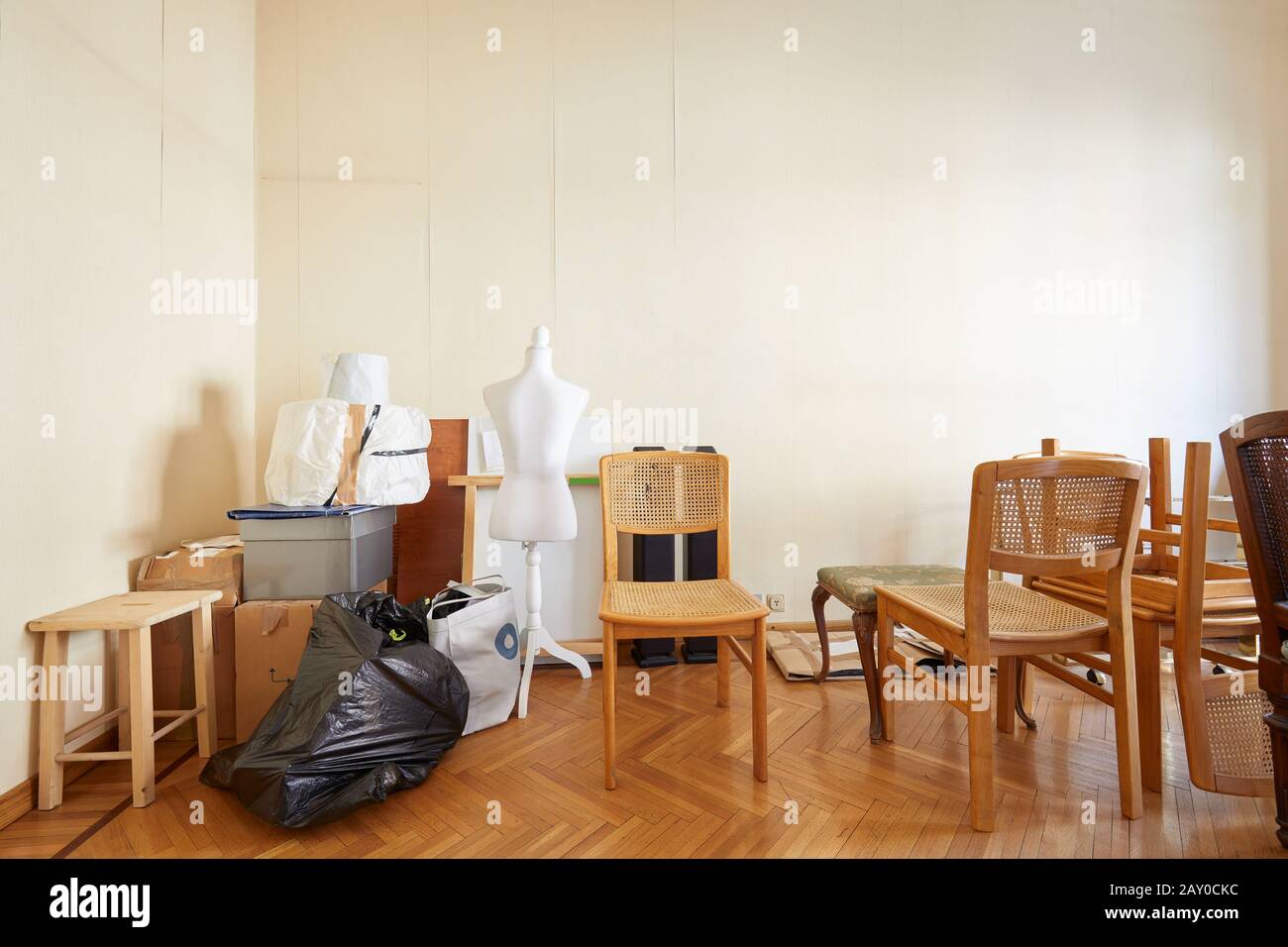 Camera con sedie, scatole e un manichino su misura prima di spostare casa Foto Stock