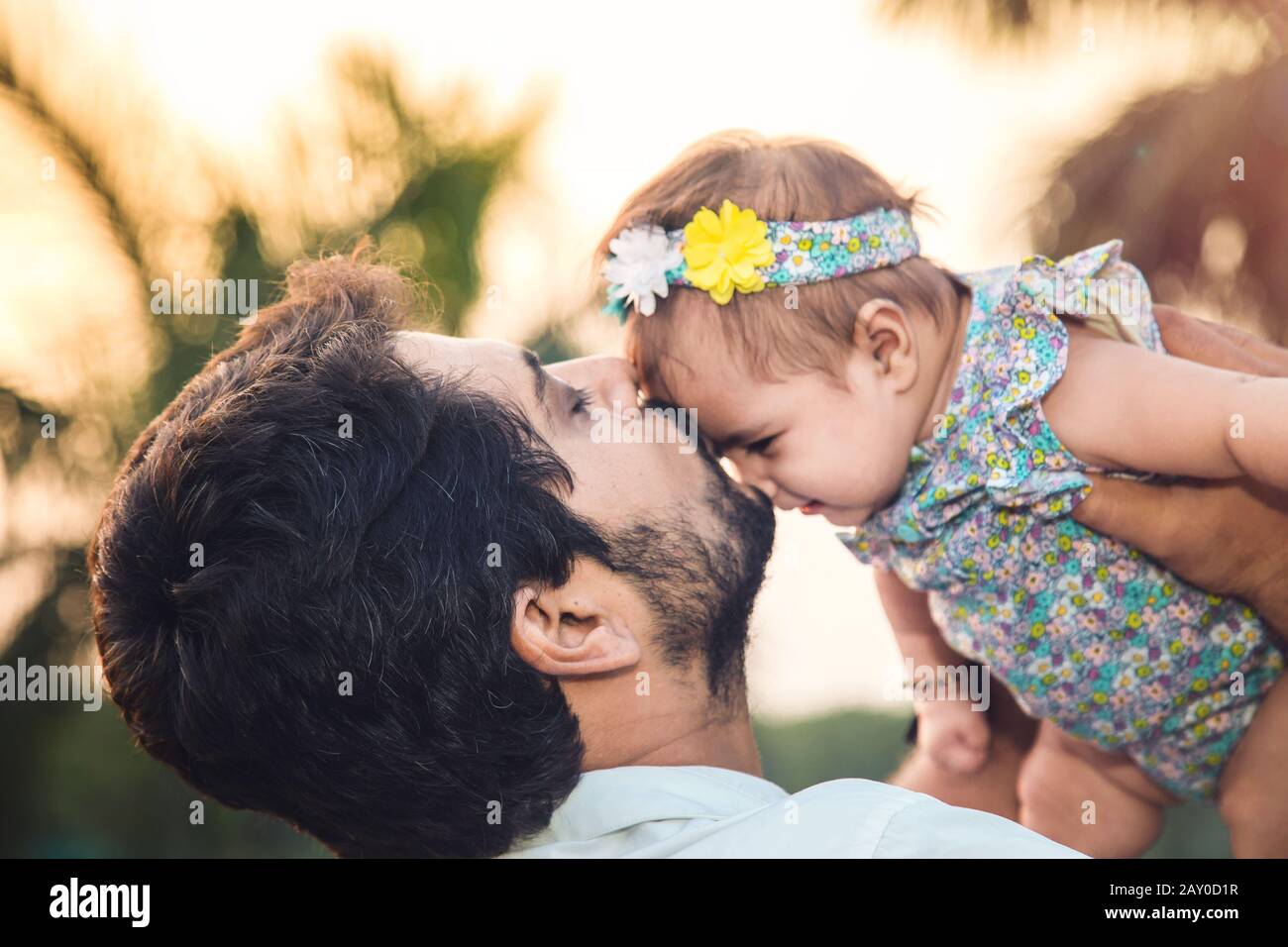 Ritratto di padre indiano felice che tiene e bacia sua figlia nel parco Foto Stock