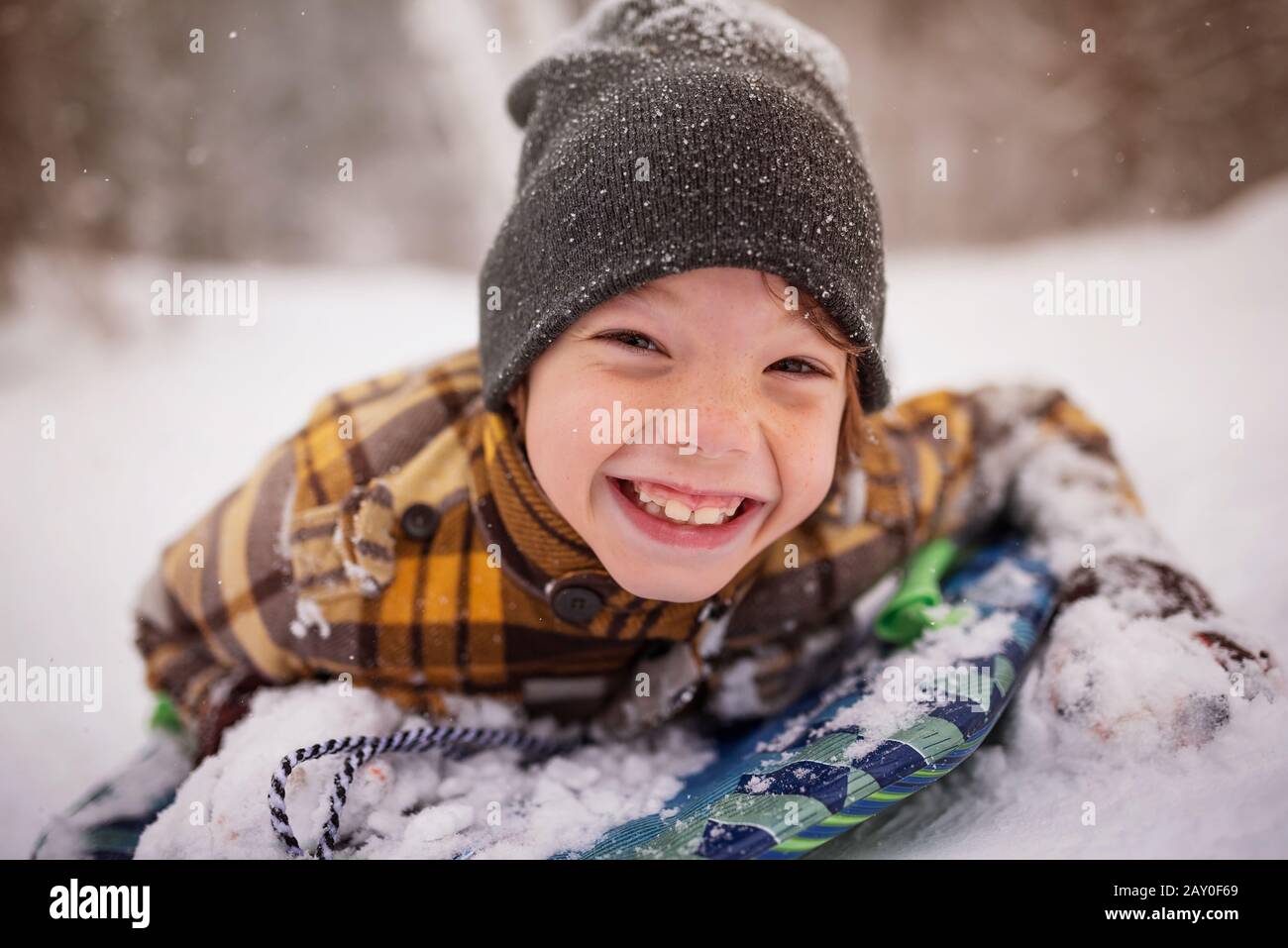 Ritratto di un ragazzo sorridente sdraiato su una slitta nella neve, Wisconsin, USA Foto Stock