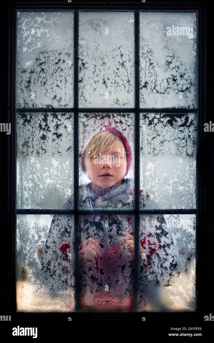 Ragazzo che guarda attraverso una finestra frosty, USA Foto Stock