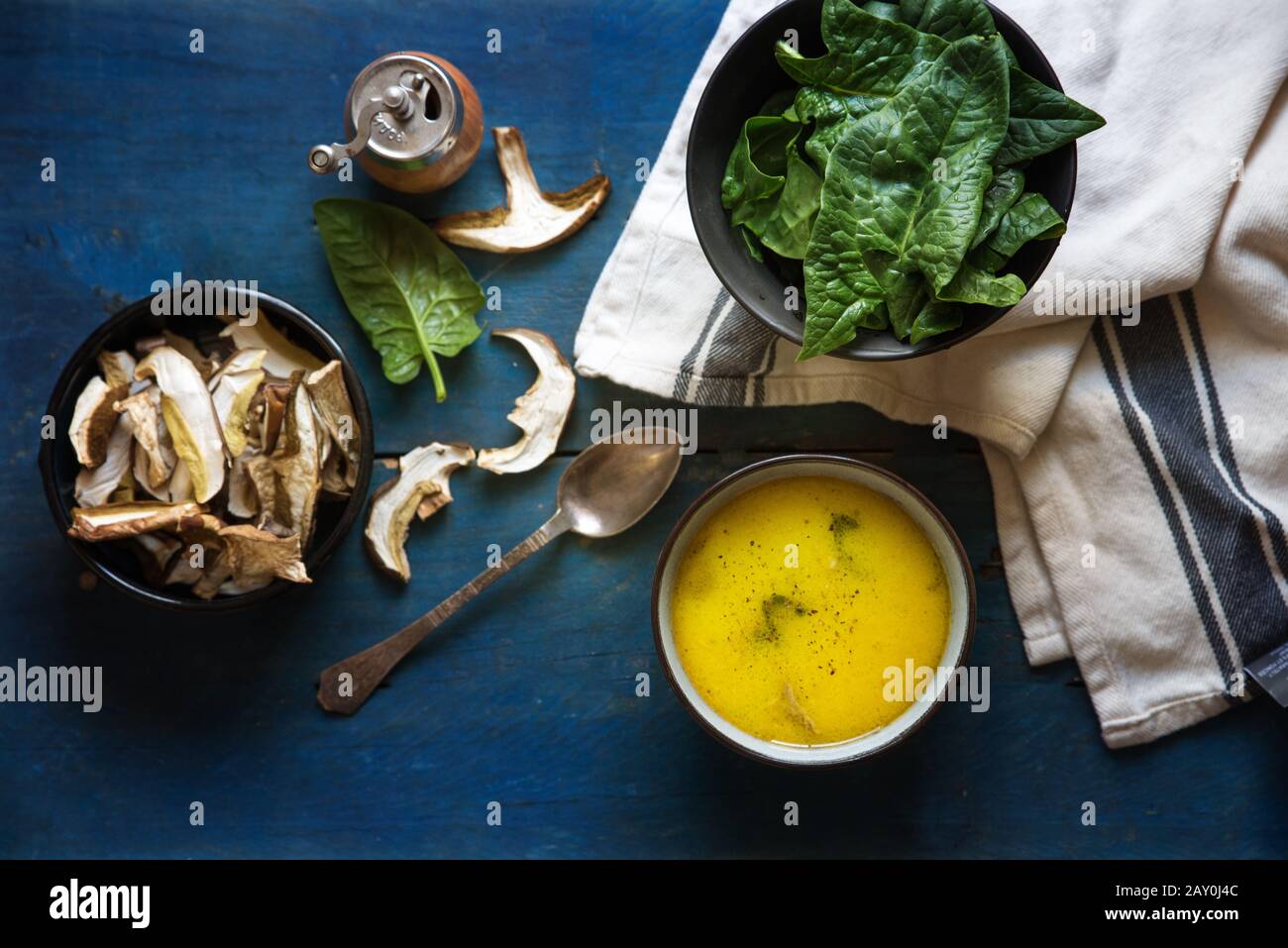 Ciotola di funghi e zuppa di spinaci accanto agli ingredienti crudi Foto Stock