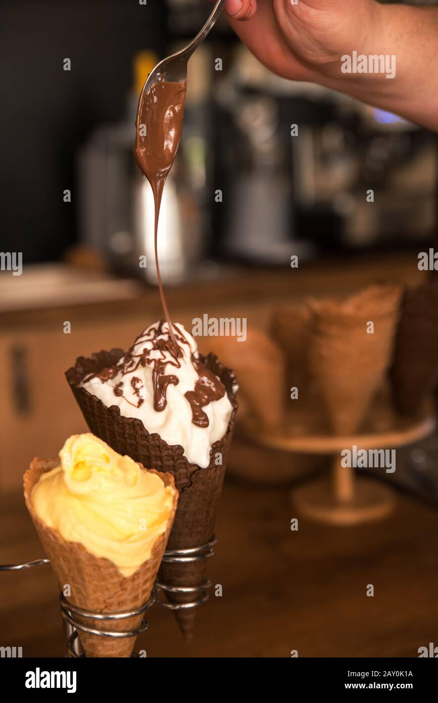 L'uomo gocciola il cioccolato fuso su un gelato Foto Stock