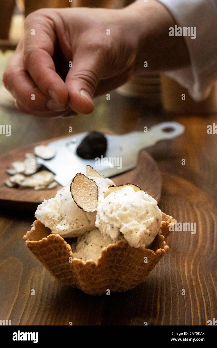 Uomo che prepara un gelato gourmet con tartufo a fette Foto Stock