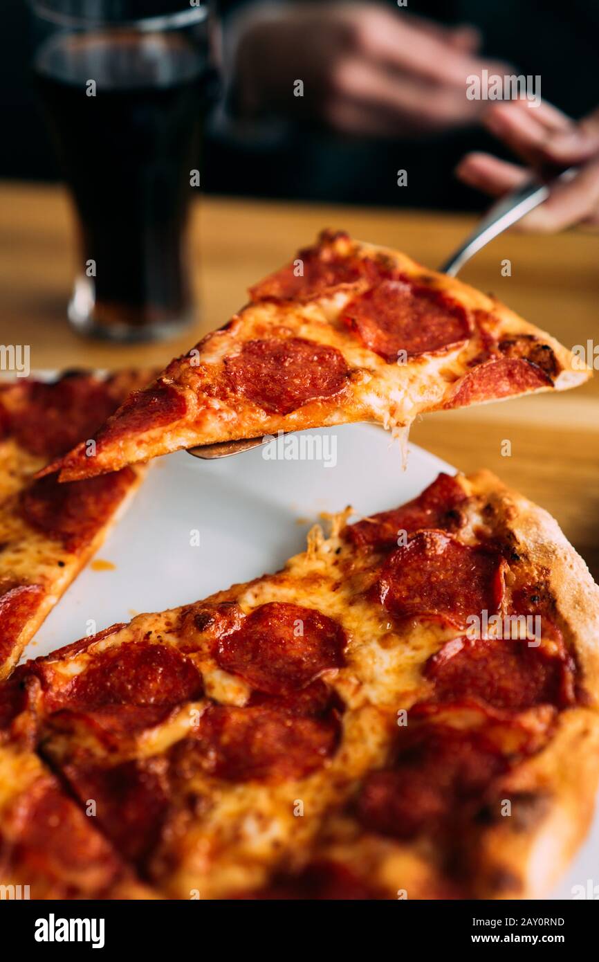 Mano umana che serve una fetta di pizza al pepe Foto Stock