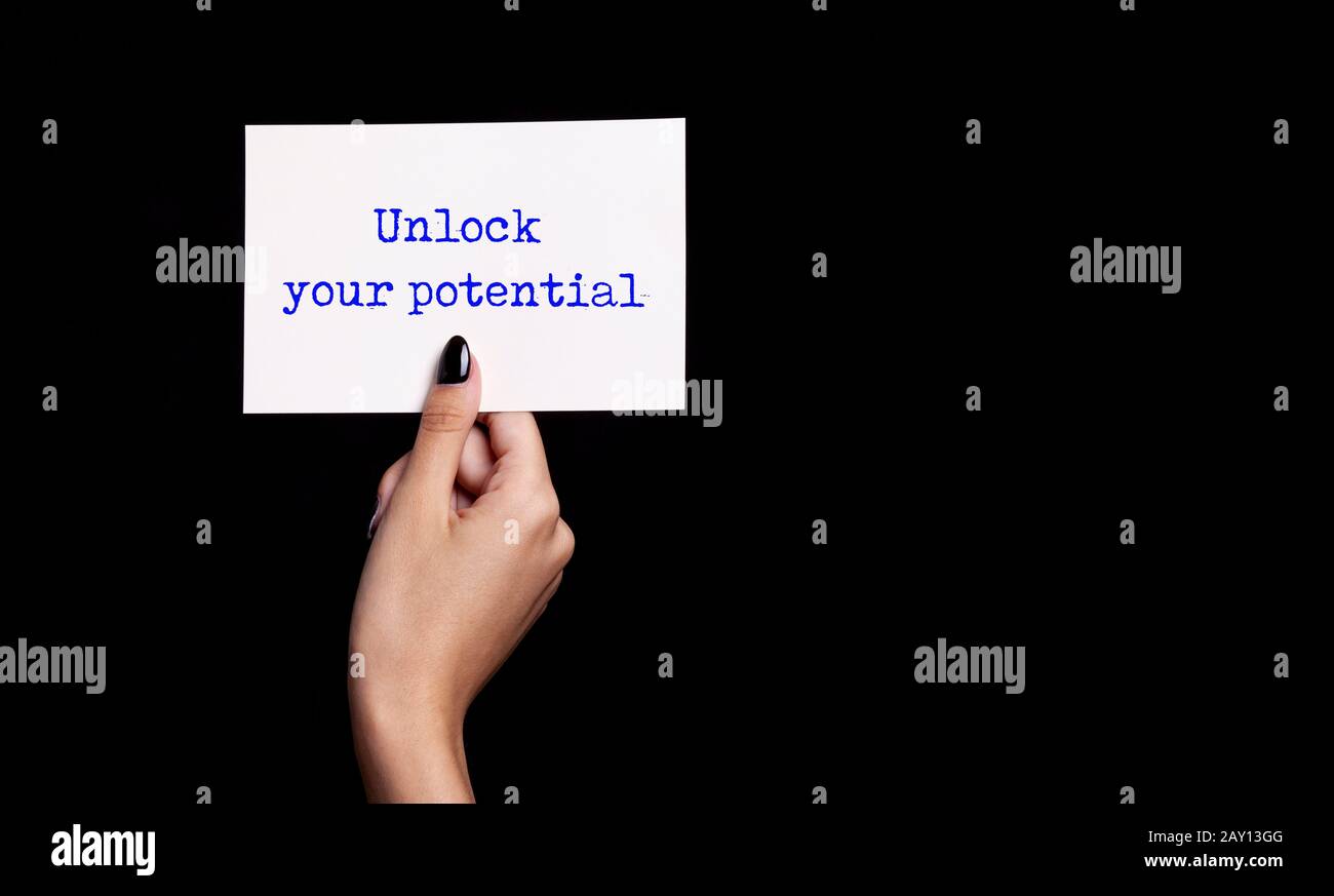 mano che tiene la carta bianca su sfondo nero - sbloccare il vostro potenziale Foto Stock