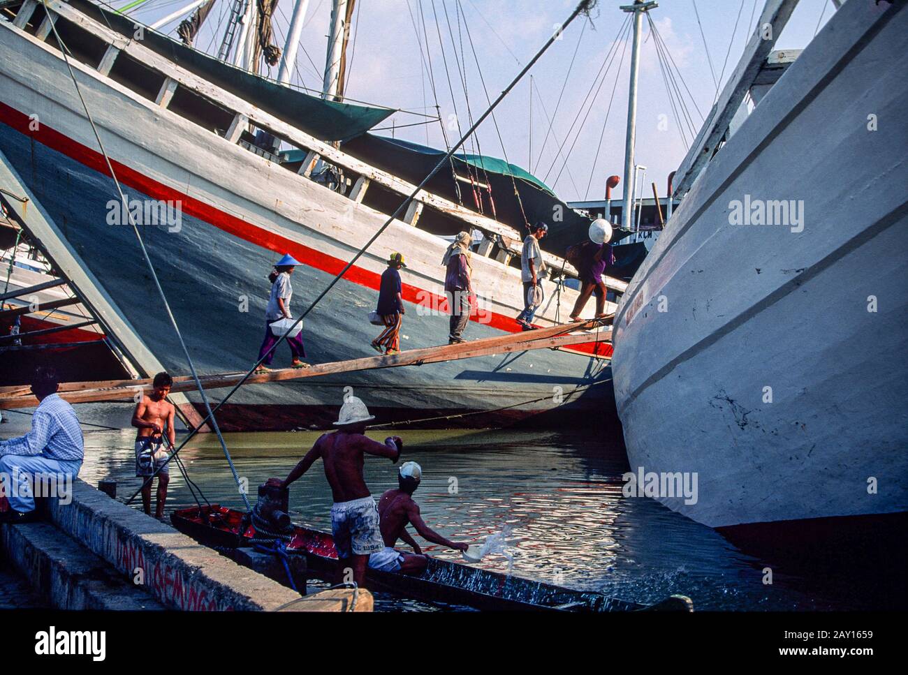 Camminando sulla plancia, facchini a bordo di barche di legno pinisi a Sunda Kelapa, Jakarta, Indonesia, giugno 1995 Foto Stock