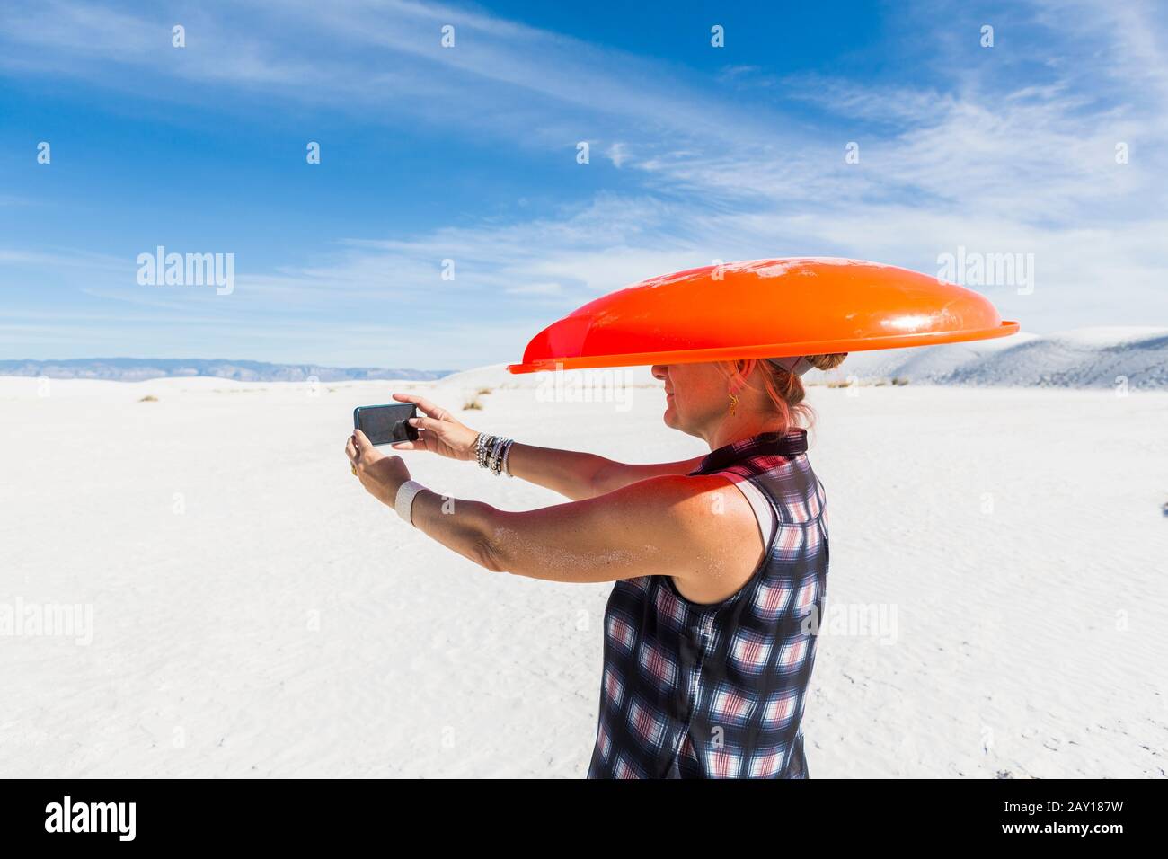 Donna che porta la slitta arancione sulla testa, prendendo selfie, White Sands Nat'l Monument, NM Foto Stock