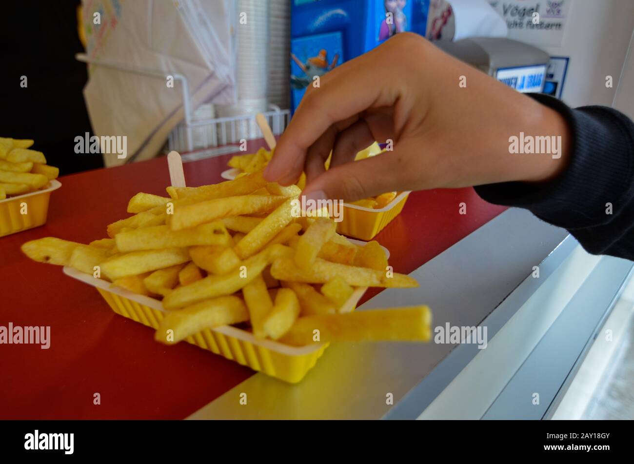 Oosterscheldekering, Paesi Bassi, Agosto 2019. La portata principale in un chiosco di cibo di strada: Patatine fritte. Una porzione è pronta per essere gustata, una mano è t Foto Stock