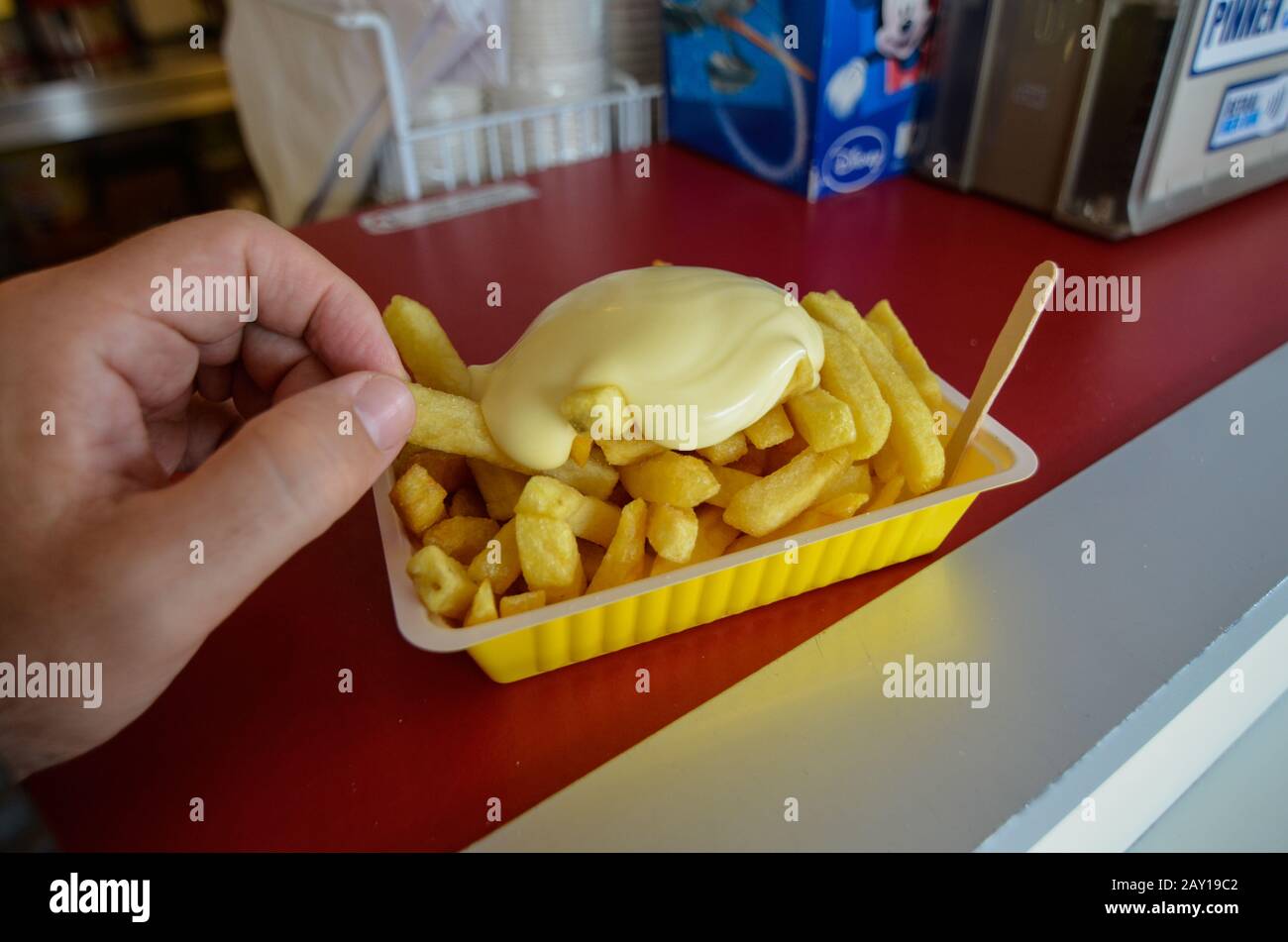 Oosterscheldekering, Paesi Bassi, Agosto 2019. La portata principale in un chiosco di cibo di strada: Patatine fritte. Una porzione è pronta per essere gustata, una mano è t Foto Stock