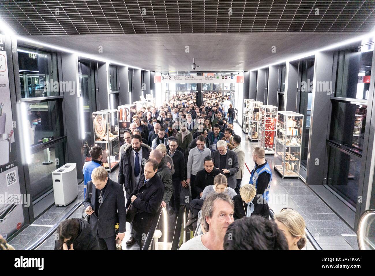 Persone in coda per la scala mobile in una fiera internazionale durante la pandemia di coronovirus, alcuni di loro indossano maschera per proteggerli Foto Stock