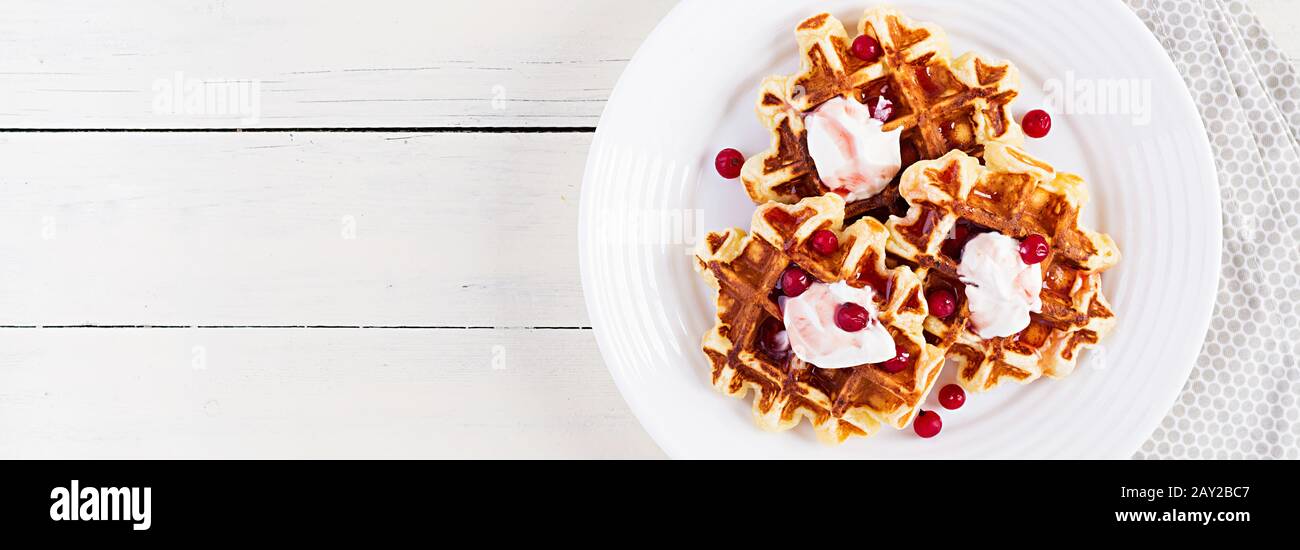 Waffle belgi tradizionali con frutti di bosco, panna acida e marmellata su tavolo di legno bianco. Vista dall'alto, banner Foto Stock