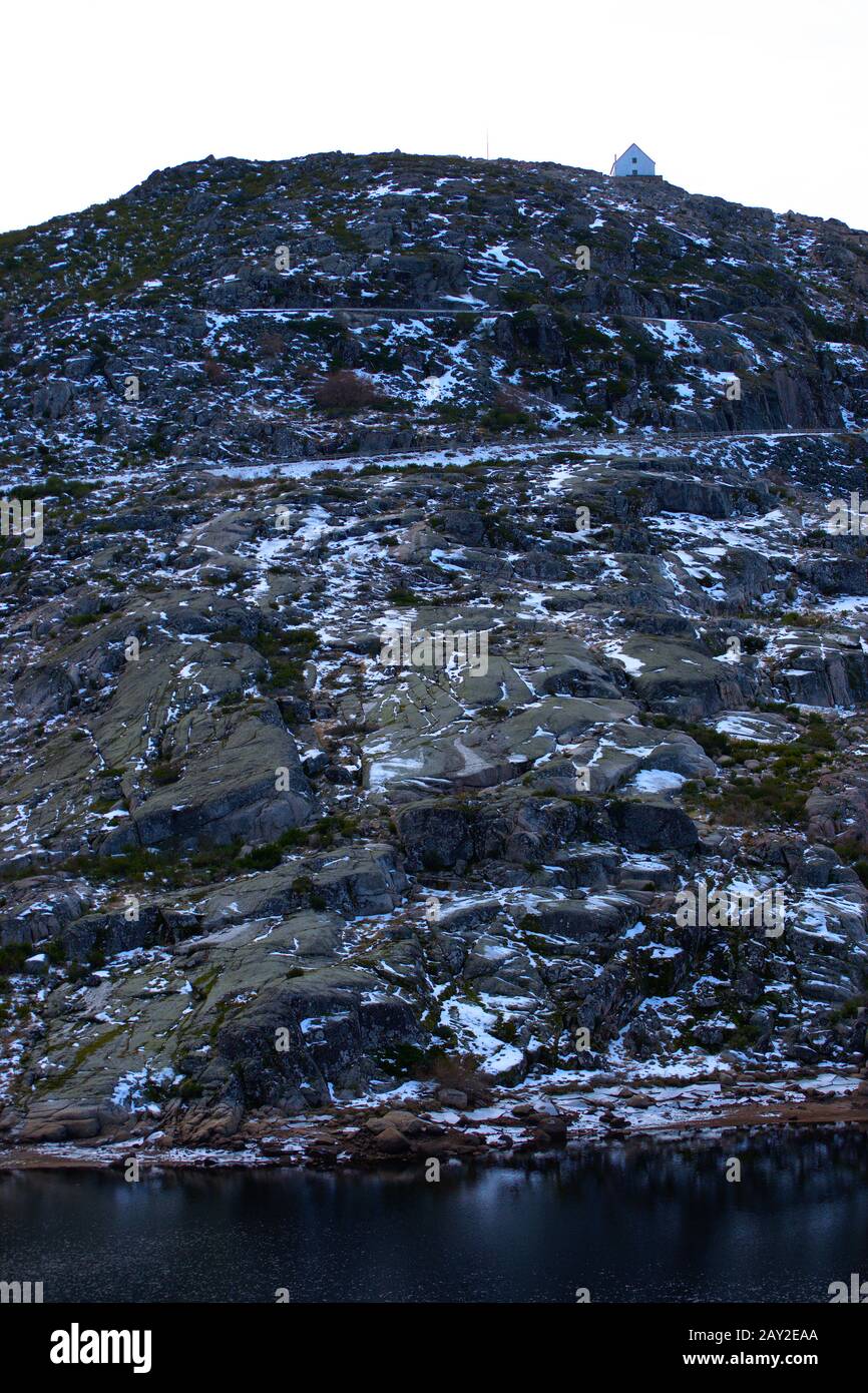 Vista laterale di una casa sulla cima di una collina di roccia leggermente coperta dalla neve Foto Stock
