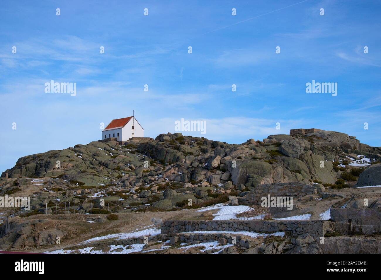 Piccola casa sulla cima di una cima di montagna coperta leggermente nevata Foto Stock