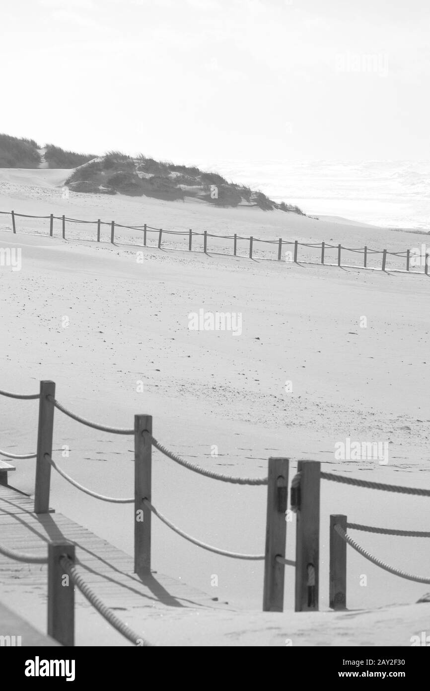 Vista in bianco e nero su una spiaggia e con passerelle e ringhiere in legno Foto Stock