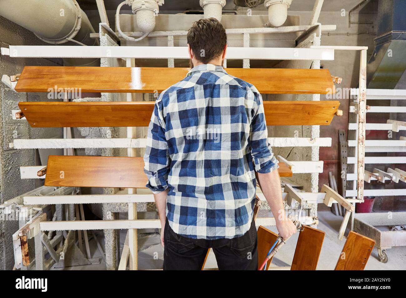 Il pittore controlla il colore della vernice o lo smalto del legno sulle parti di mobilia nel negozio di vernice Foto Stock