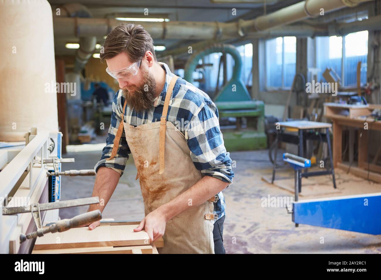 Falegname tirocinante nella levigatura del legno per la costruzione di mobili nella carpenteria Foto Stock