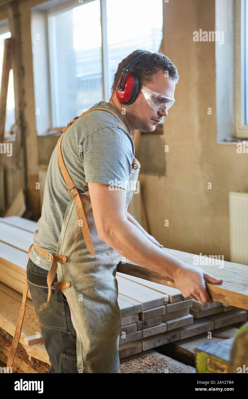 Apprendista falegname con protezione uditiva e occhiali di sicurezza quando si lavora con il legno Foto Stock