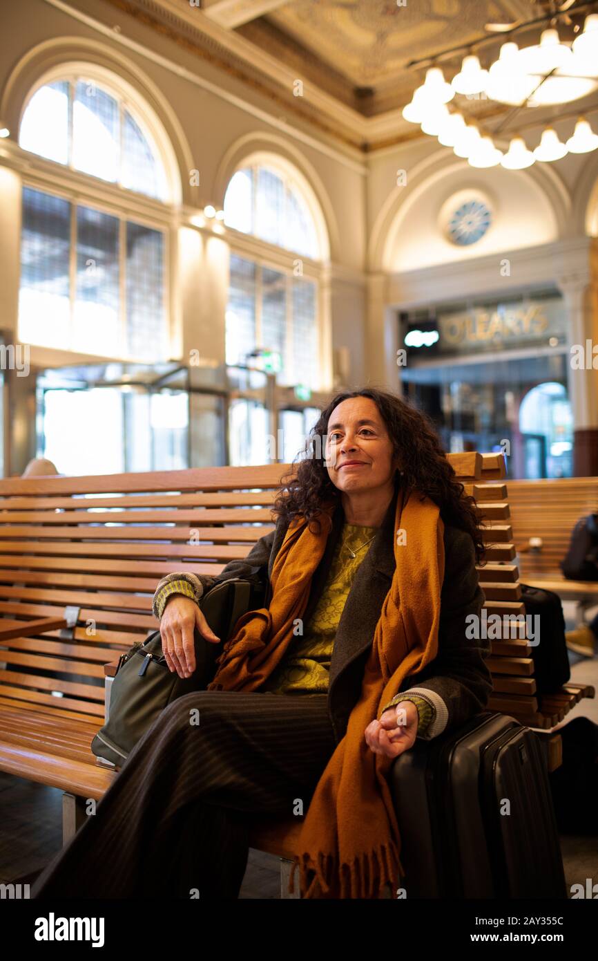 Donna in attesa sulla stazione ferroviaria Foto Stock