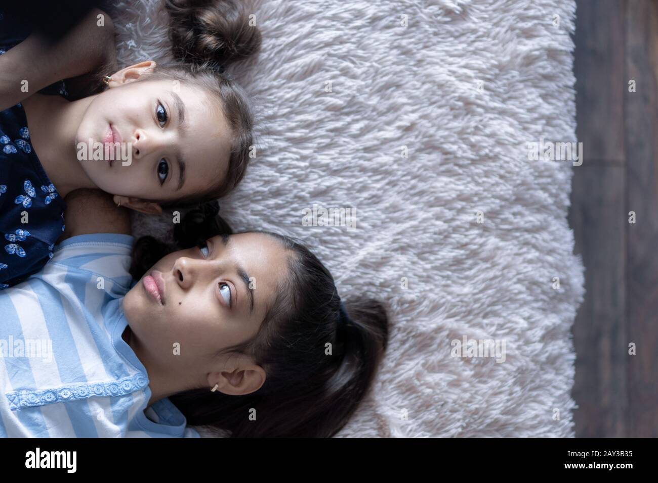 Due ragazze, sorelle, giovani del Medio Oriente sdraiati sul letto e guardate lo smartphone nei raggi del sole. Ragazze persiane sul letto con un telefono Foto Stock