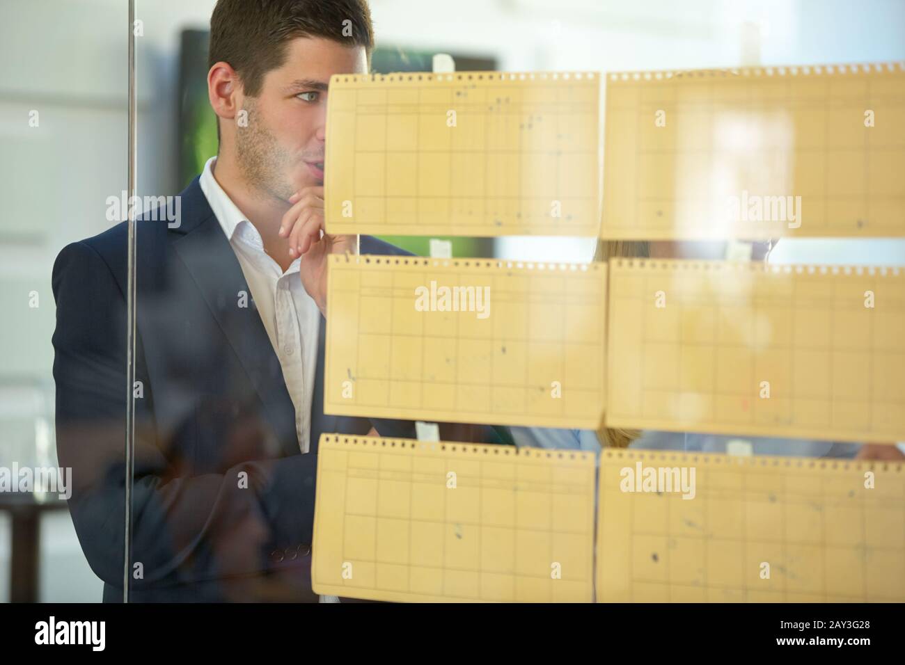 Il gruppo fa il brainstorming di affari con le note su una parete di vetro Foto Stock