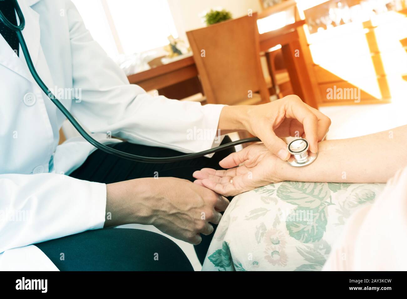 closeup di un medico caucasico, in una mano bianca, che prende l'impulso ad una donna di pazienti caucasici anziani con uno stetoscopio, a casa sua o a un nursi Foto Stock