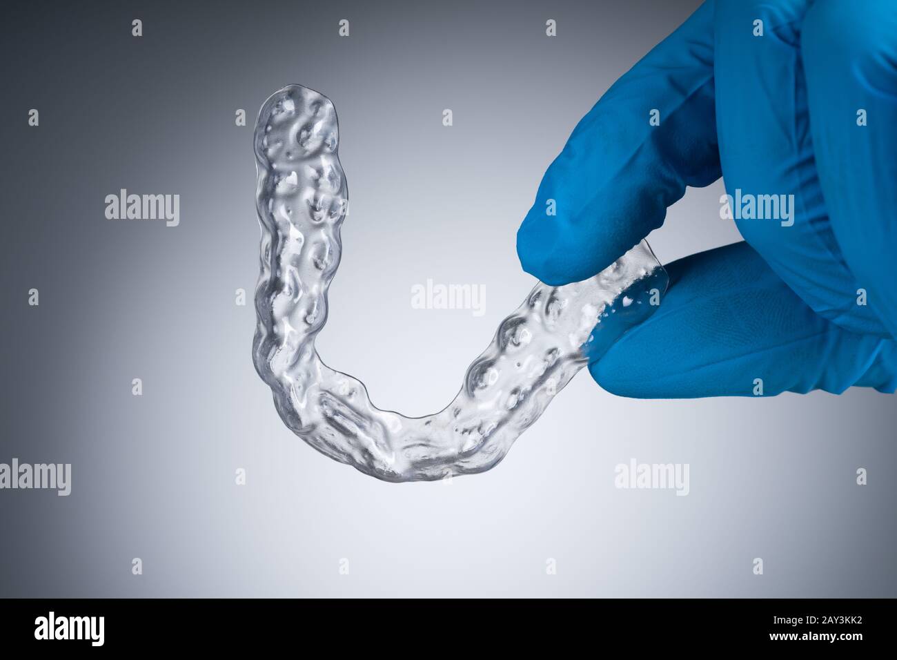 Primo Piano Delle Bretelle In Plastica Trasparente Con Tenuta Manuale Dentista Sullo Sfondo Grigio Foto Stock