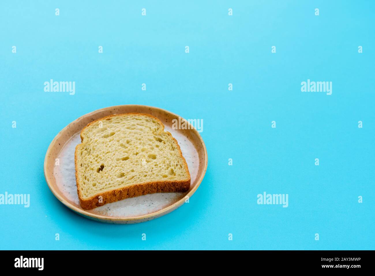 Pezzo di pane su piastra moderna e sfondo blu chiaro Foto Stock