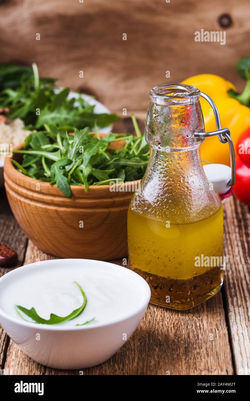 Yogurt greco e insalata fatta in casa, preparazione di insalata fresca con verdure, erbe e ceci su un rustico tavolo di legno Foto Stock