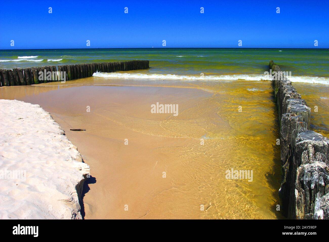 Variopinto mare della costa del Mar Baltico e spiaggia di sabbia nella città di Karwia, nel nord della Polonia, con resti di strutture in legno di frangiflutti Foto Stock