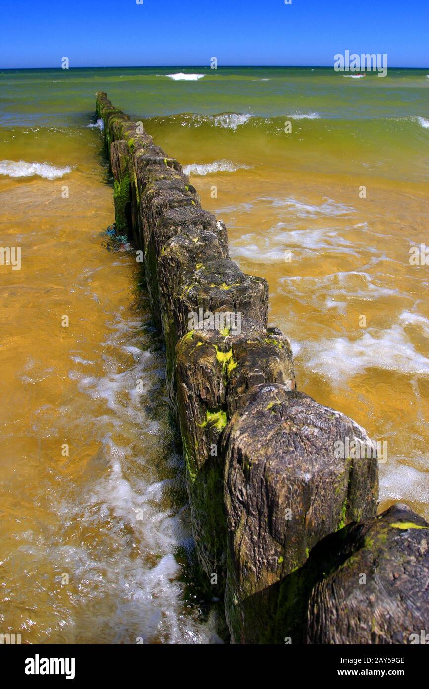 Variopinto mare della costa del Mar Baltico e spiaggia di sabbia nella città di Karwia, nel nord della Polonia, con resti di strutture in legno di frangiflutti Foto Stock