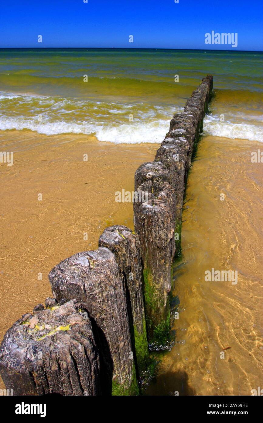 Variopinto mare della costa del Mar Baltico e spiaggia di sabbia nella città di Karwia, nel nord della Polonia, con resti di strutture in legno di frangiflutti Foto Stock