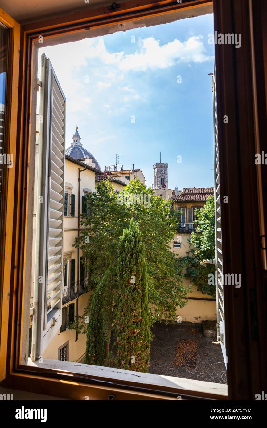 Si affaccia sulla finestra dell'Hotel Europa di Firenze. La cima del Duomo e il campanile si possono vedere sopra i tetti. Foto Stock