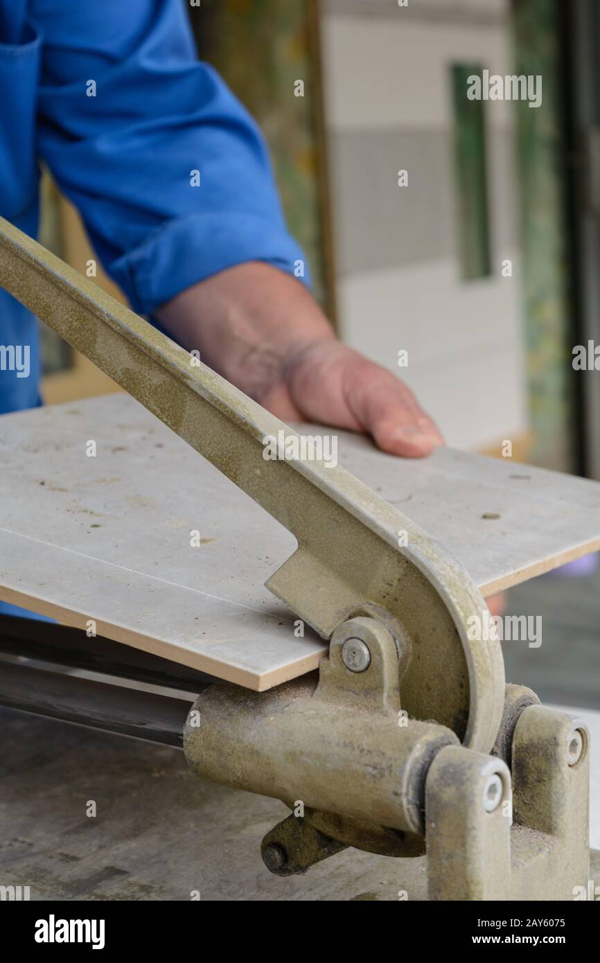 lavoratore specializzato taglia e rompe piastrelle alla giusta taglia Foto Stock