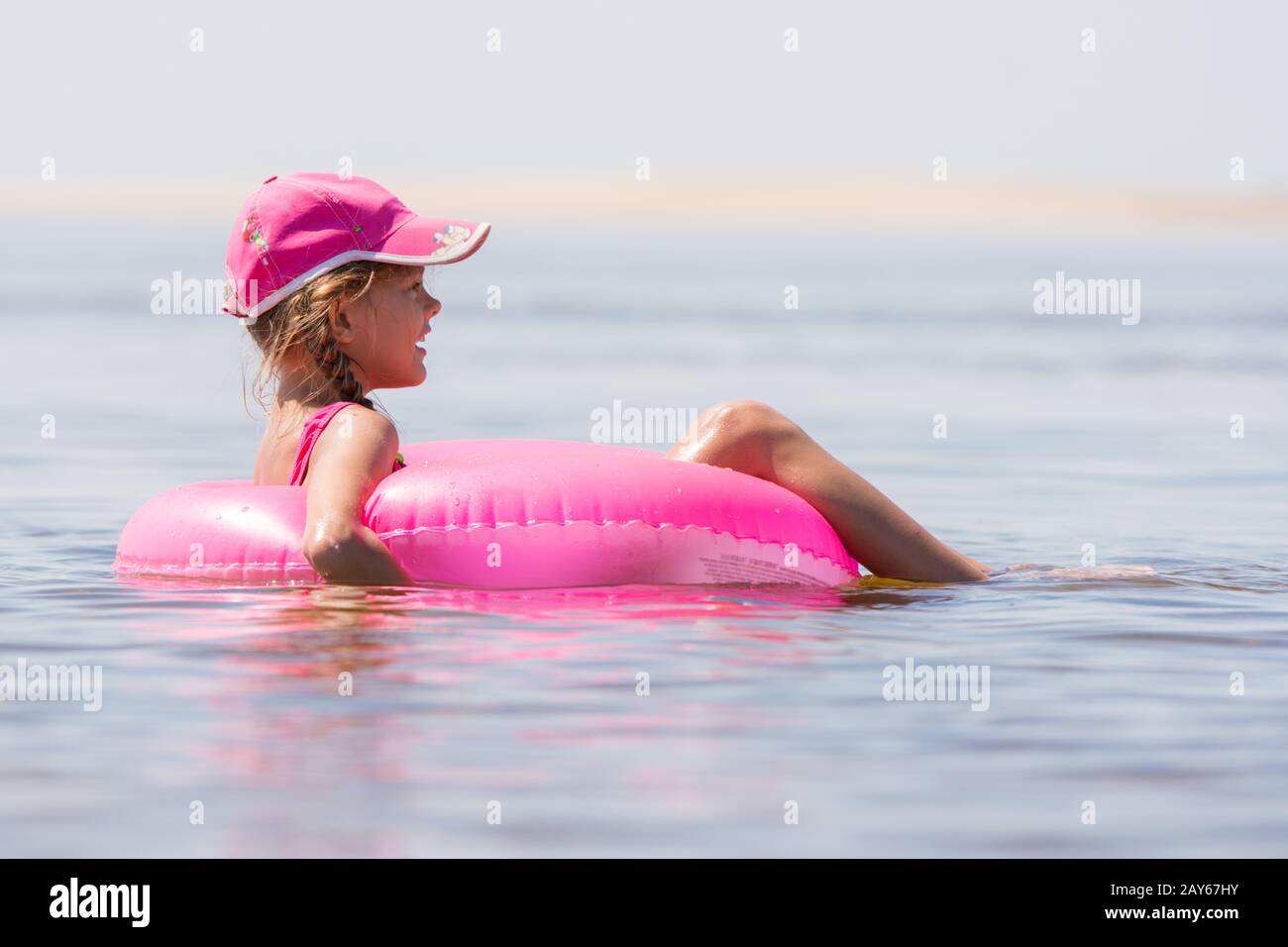 La ragazza nel cappuccio nuotare nel fiume sat sul cerchio di nuoto Foto Stock
