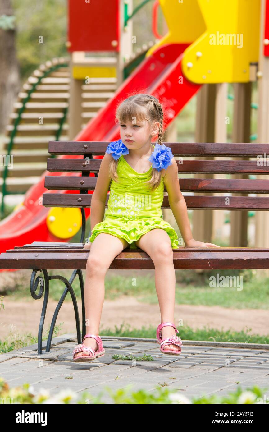 Sconvolto ragazza seduta sul banco di lavoro sullo sfondo del parco giochi Foto Stock