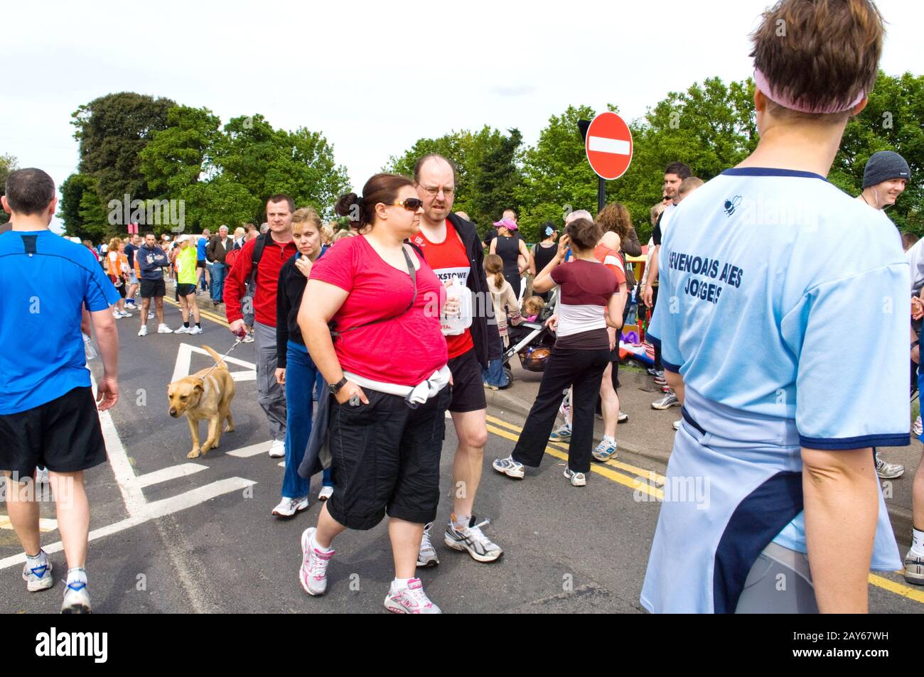 Gruppi di persone e corridori che si raccolgono sulla strada prima dell'inizio di UNA corsa di beneficenza 10KM. Donna sovrappeso in primo piano con runner. Foto Stock