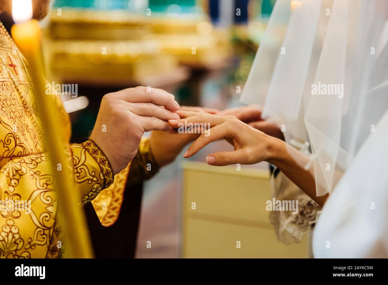 Il sacerdote mette in anello sul dito di sposa durante la cerimonia nuziale della chiesa. Scambio di anelli. Vista orizzontale. Concetto di matrimonio Foto Stock