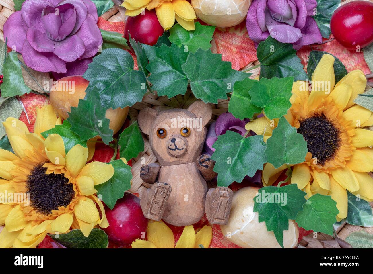 Modello di biglietto d'auguri. Primo piano di una bella e colorata gestione di fiori artificiali e petali e piccolo e divertente orso di legno nel centro. Garee Foto Stock