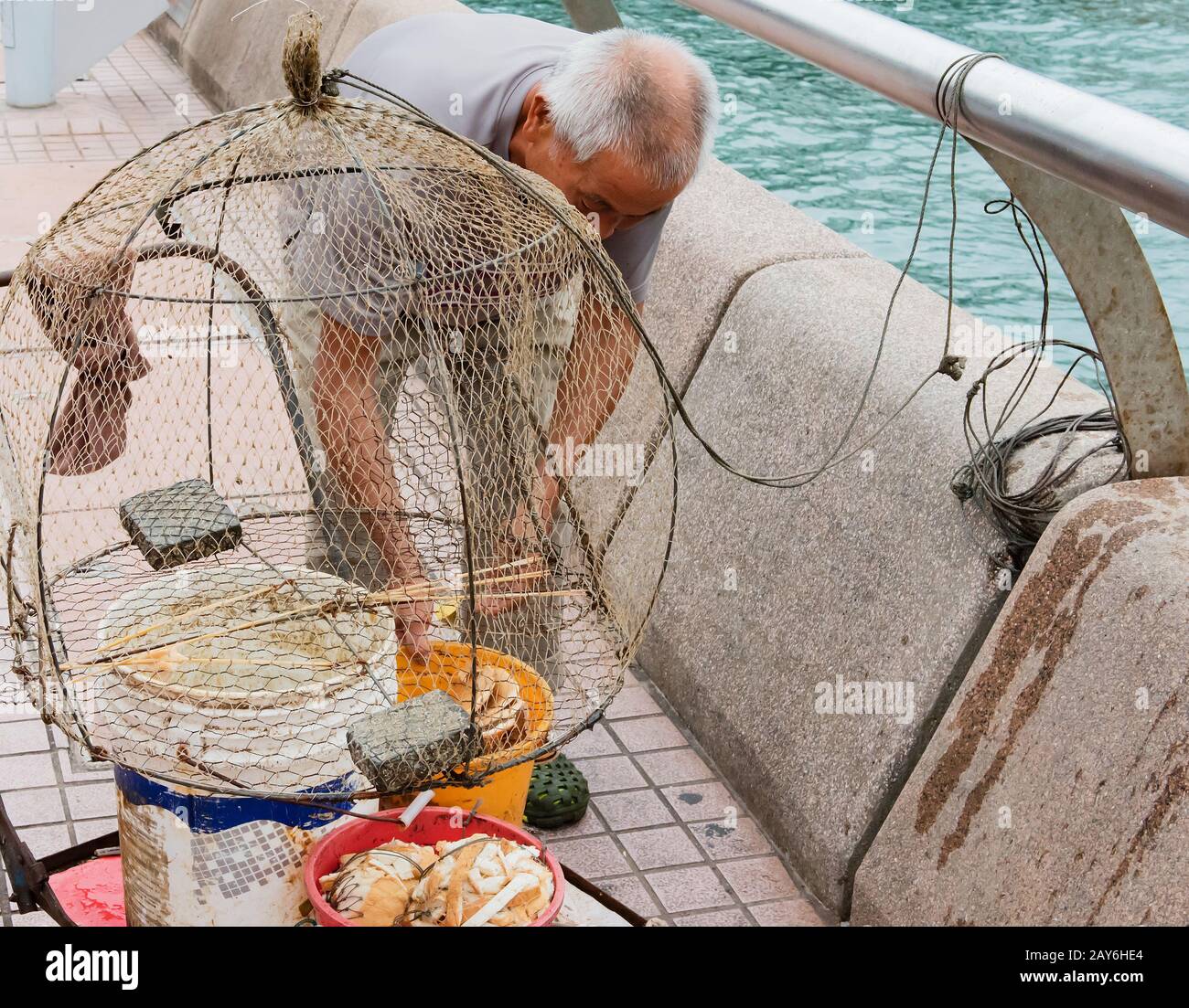Vecchio pescatore cinese con la sua rete di pesca al porto Victoria di HongKong Foto Stock